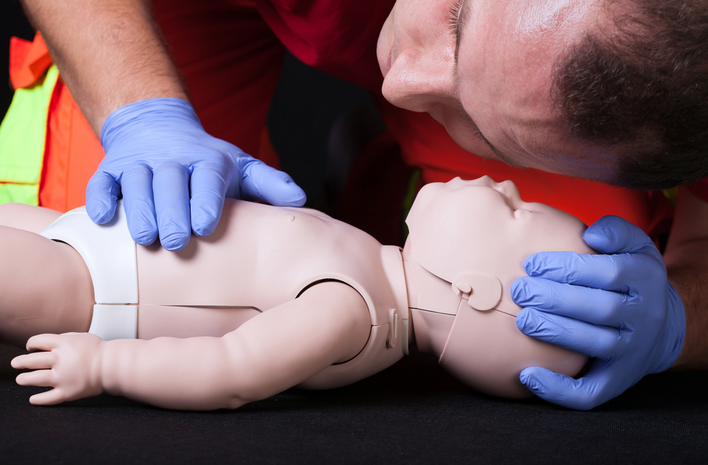 Paramedic demonstrating life function check on infant dummy-1
